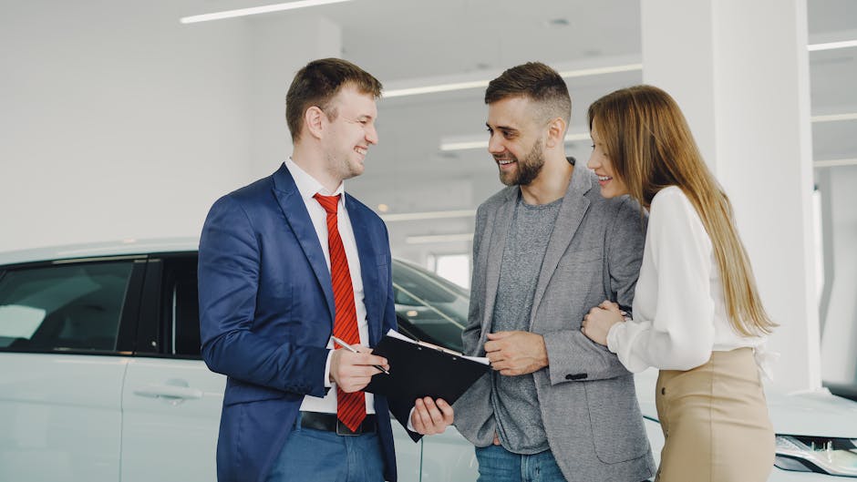 A smiling couple buys a new car from a confident salesman inside a modern car dealership