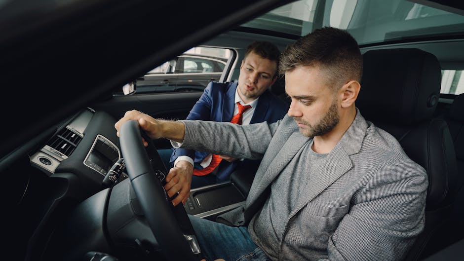 Salesman demonstrating car features to potential buyer inside vehicle showroom.