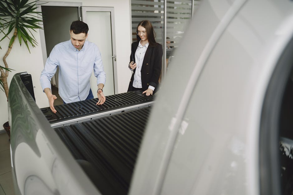 Salesman and client inspecting a pickup truck in a car dealership, discussing features