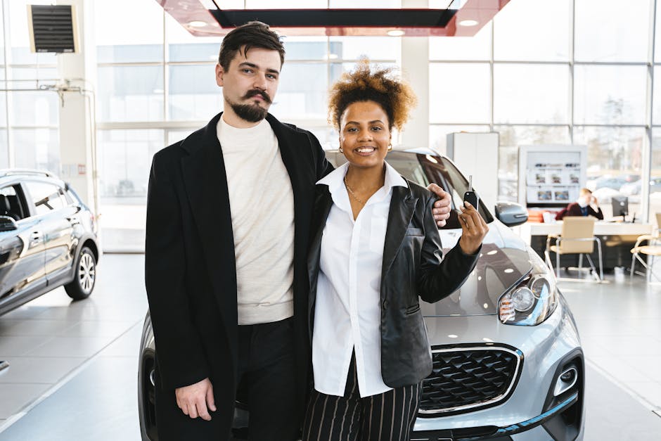Interracial couple celebrates buying a new car at a dealership, holding keys and smiling